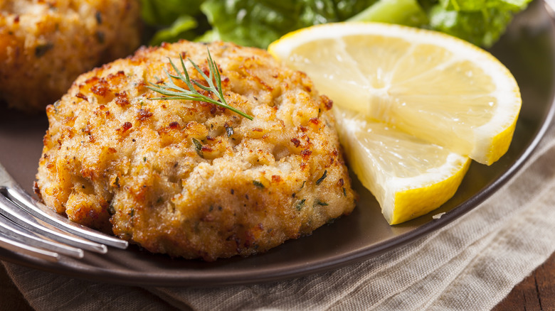 Cooked crab cakes on a plate with greens and lemon