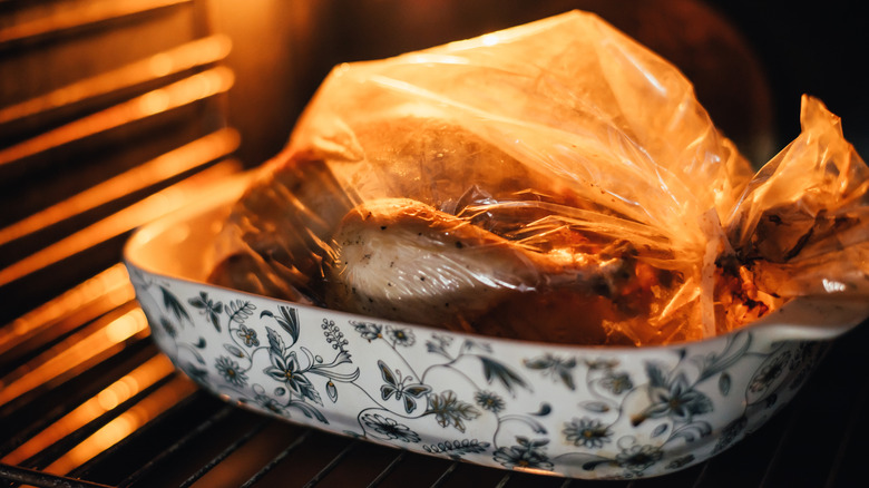 A whole turkey cooking in an oven bag, inside a casserole dish