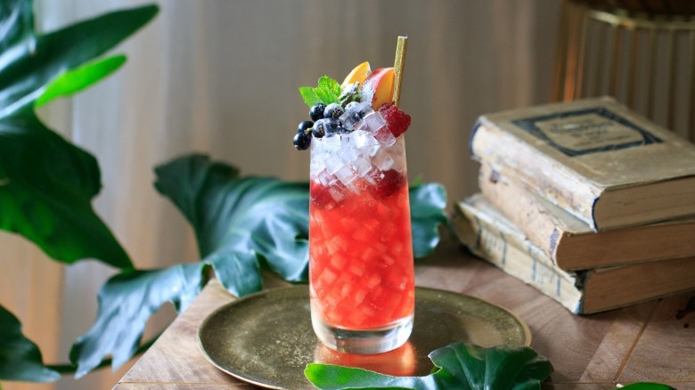 A sherry cobbler in a collins glass next to antique books