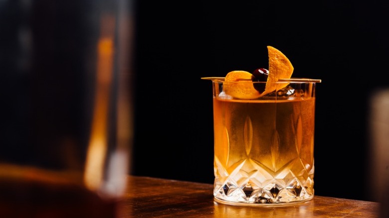 An Old Fashioned cocktail with garnish, on a bar counter