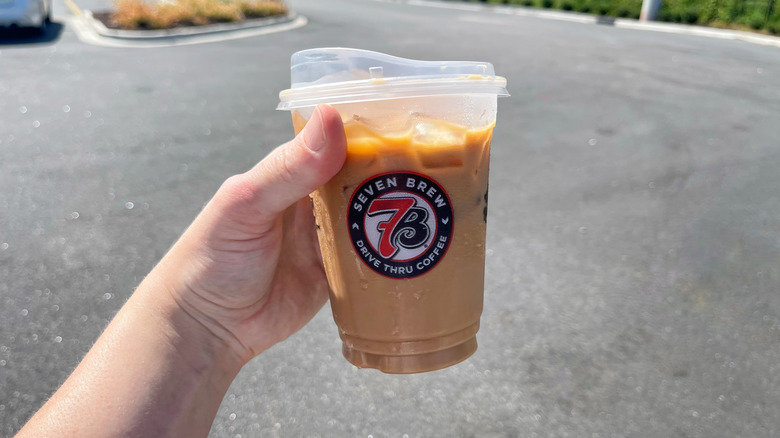 The Brunette coffee from 7 Brew held in a hand in a parking lot