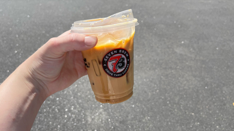 The Cinnamon Roll coffee in a 7 Brew cup held by a hand