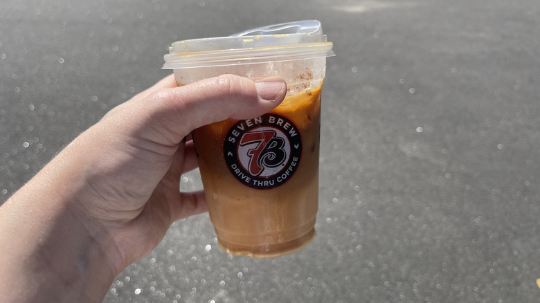 The Blackberry Cobbler coffee in a 7 Brew cup held in a hand