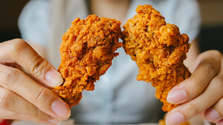 person holding up two pieces of fried chicken