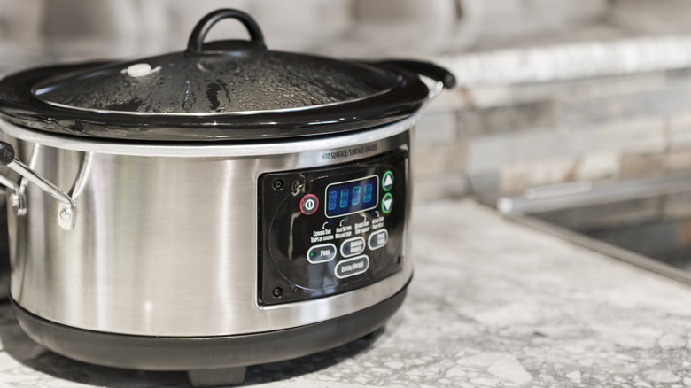 A close up of a slow cooker on a counter top.