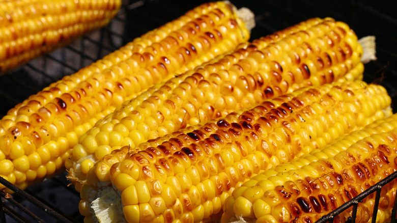 A close up of five ears of corn on a grill