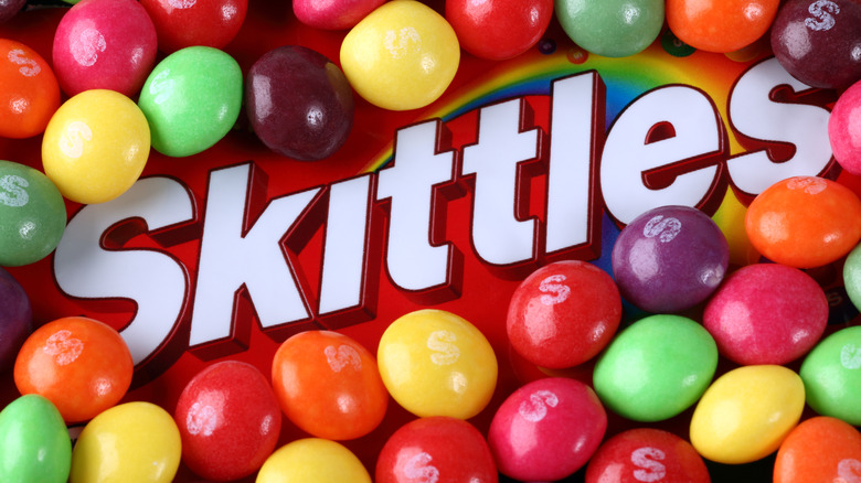 A skittles package surrounded by skittles