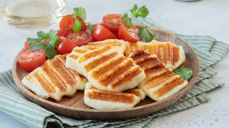 Seared haloumi cheese on a plate with tomato halves