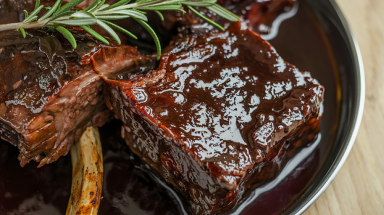 Braised short ribs in red wine sauce with a sprig of rosemary