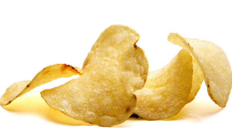 several yellow potato chips on white background