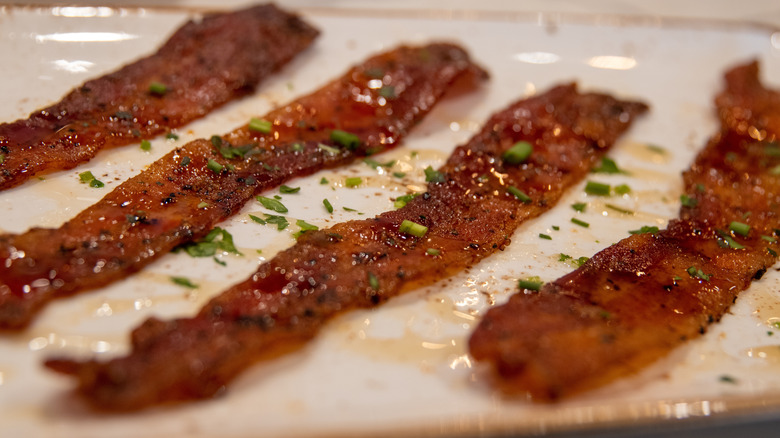 Four strips of candied bacon on a white plate