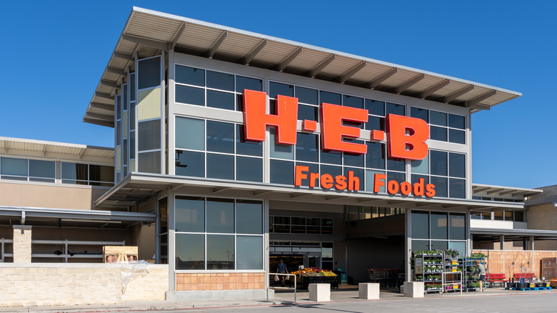 Angled view of an H-E-B grocery façade under a clear, bright-blue sky