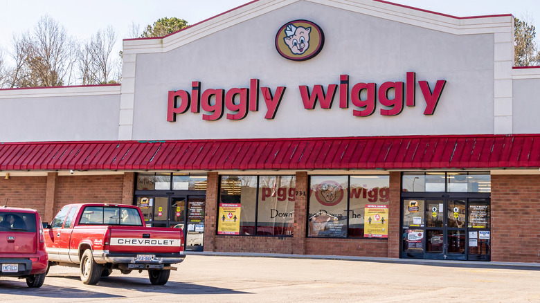 A Piggly Wiggly store façade with a red Chevy pick-up and Kia Soul in the parking lot