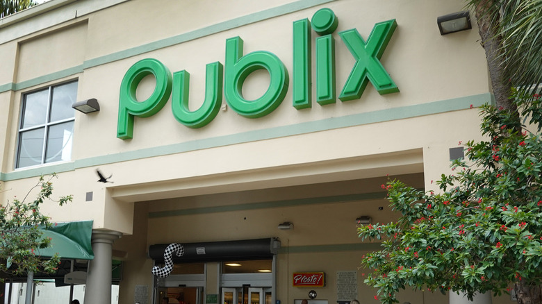 A close-up of a green Publix sign over the store's entryway surrounded by foliage
