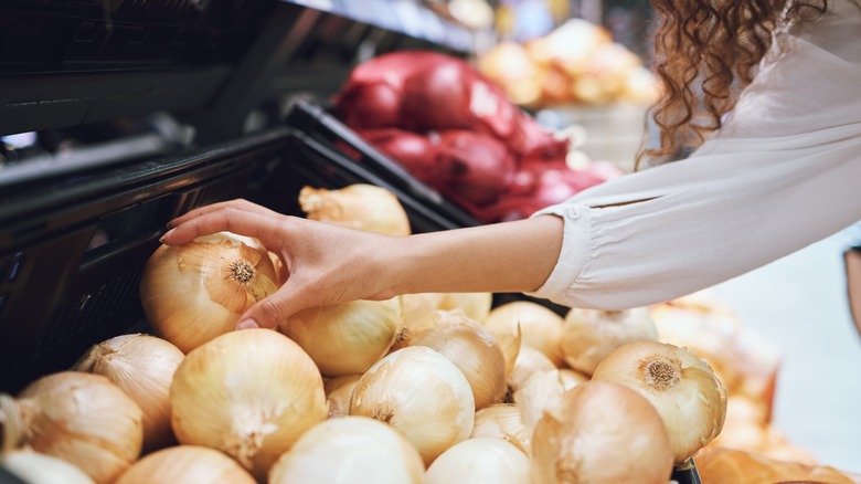 woman grabbing onion at grocery