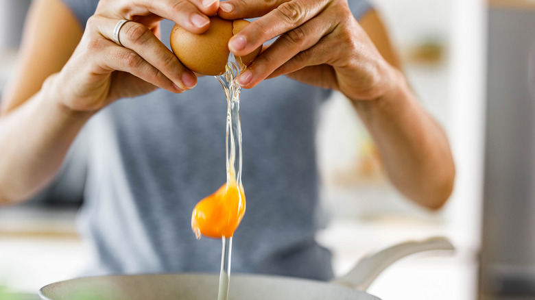 Woman cracking egg into pan