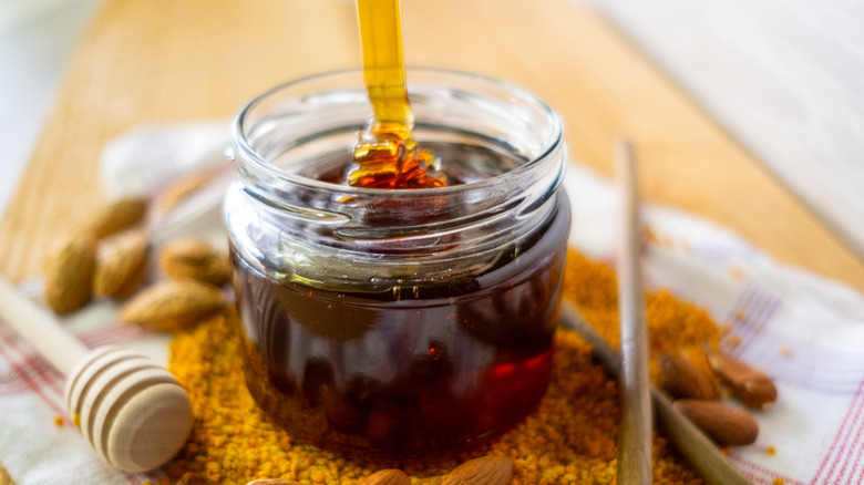 Thick honey drizzling into a jar