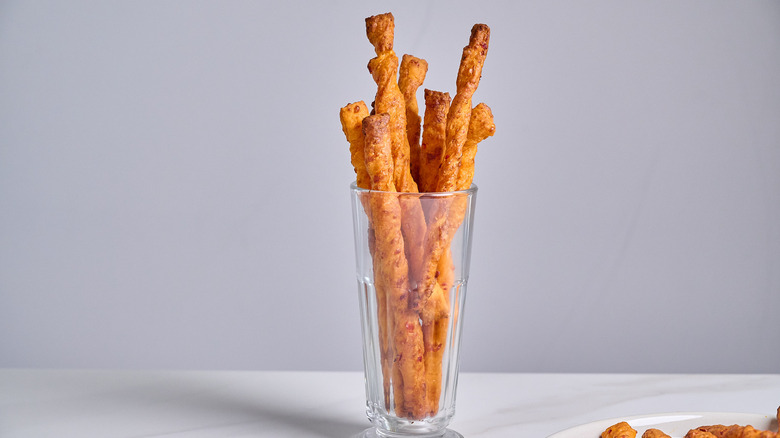cheese straws standing vertically in a glass