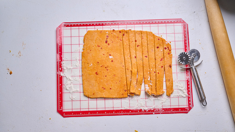 slicing dough into strips using a pastry cutter