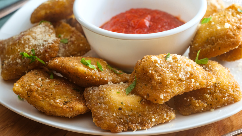 Toasted ravioli on a plate with marinara sauce.