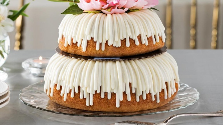 Stacked bundt cake with white icing and pink flowers