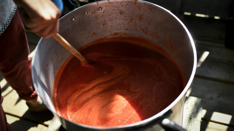 Fresh tomato sauce being stirred by a wooden spoon in a large pot