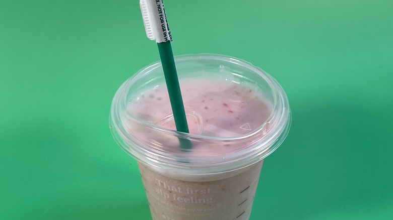 A blended Energy Refresher with a straw on a green background