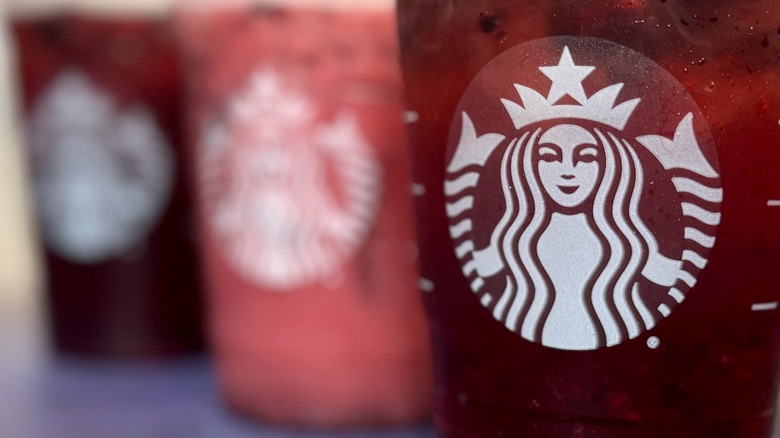 Close-up of Starbucks logo and three drinks in plastic cups.