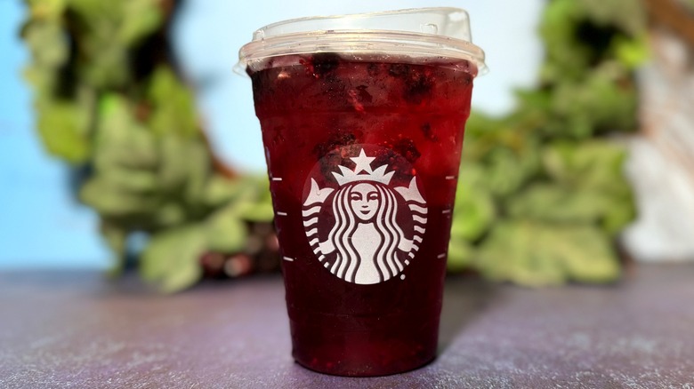 Deep red Starbucks refresher in branded plastic cup.