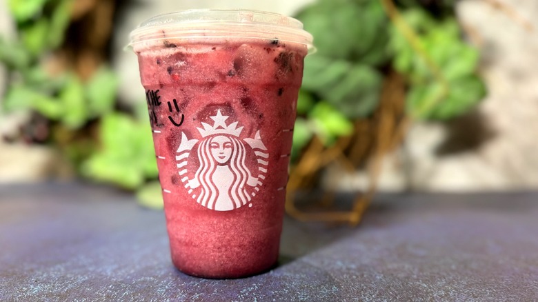 Milky red Starbucks Midnight Drink in branded plastic cup.