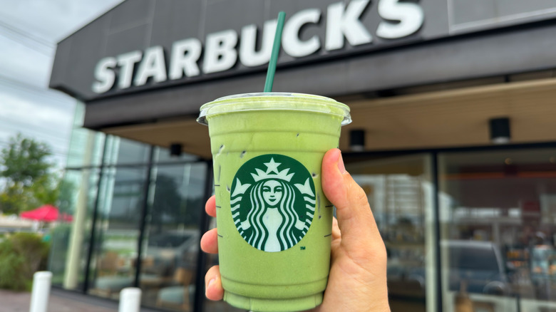 Starbucks drink held in front of Starbucks store