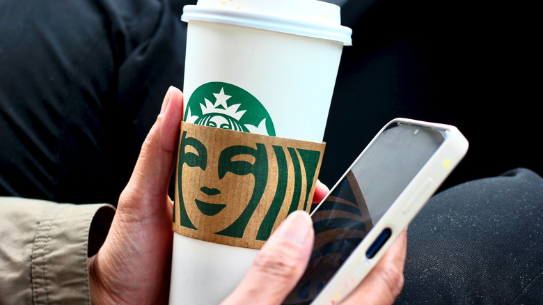 Hand holding phone and Starbucks cup