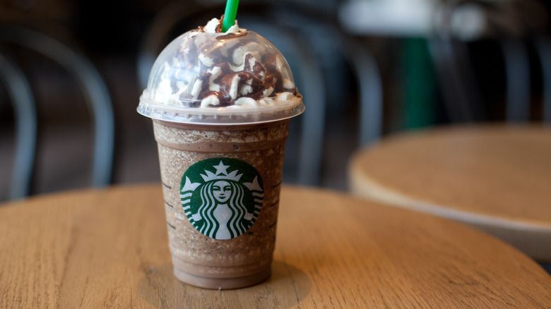 Grande Starbucks Frappuccino on wooden table in store.