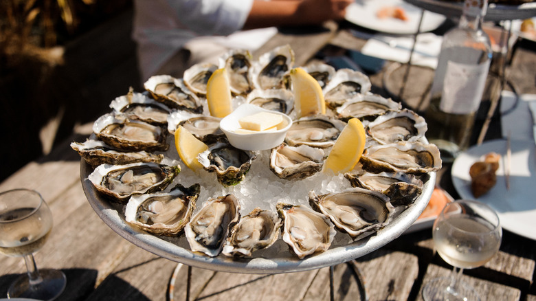 Platter of oysters on a half shell with lemon and butter