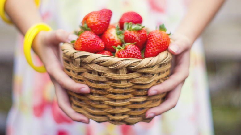 Person holding basket of strawberries