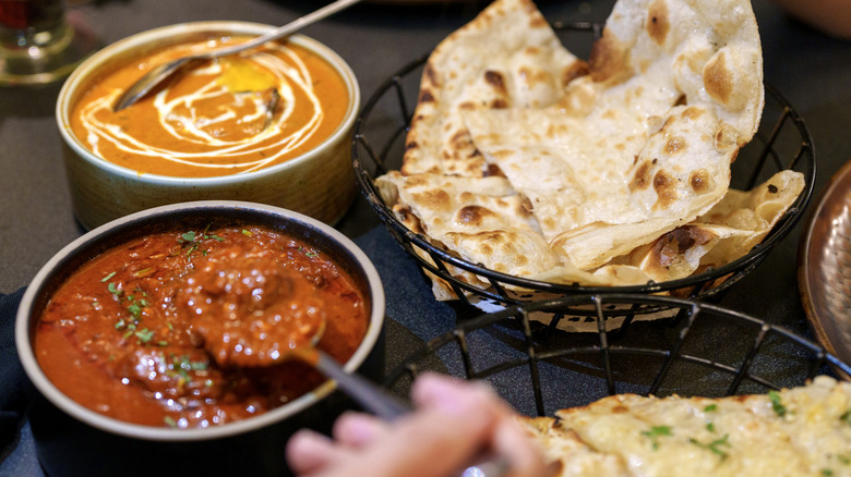 Two types of curries and naan on a table at an Indian restaurant