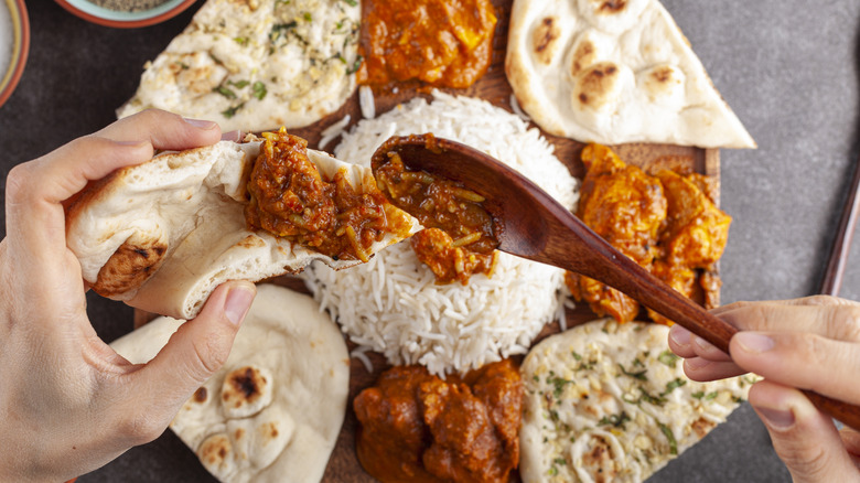 A person placing rice mixed with curry on naan with a wooden spoon
