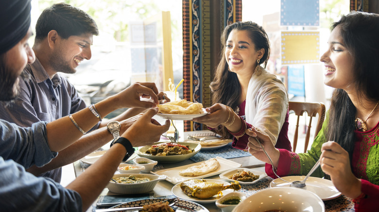 Four people sharing Indian food at a restaurant