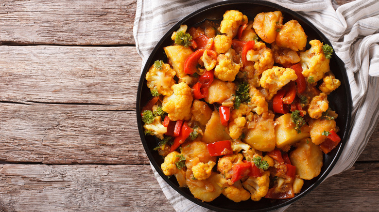An Indian main dish of aloo gobi on a wooden table