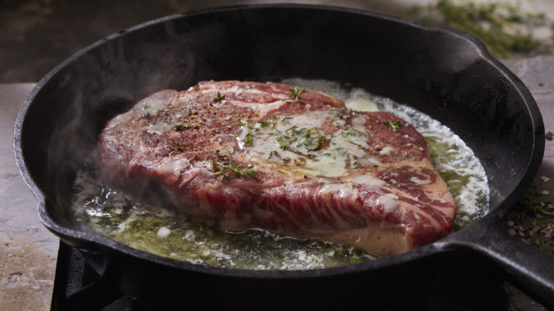 Steak in a cast-iron pan with rosemary and lots of butter