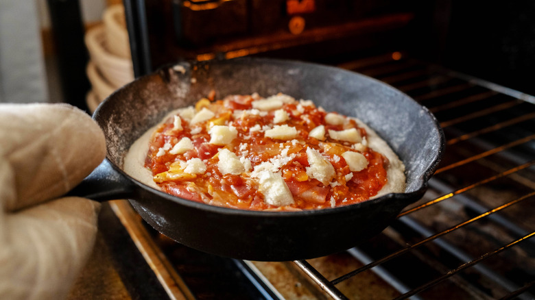Pizza in a cast iron pan in an oven