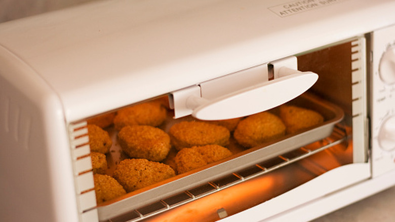 Chicken nuggets on a metal sheet tray in a white toaster oven