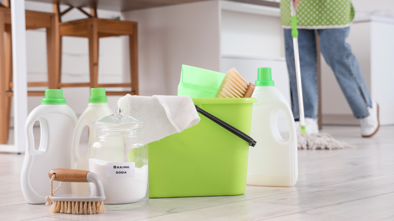 Natural cleaning products with person mopping kitchen floor in background