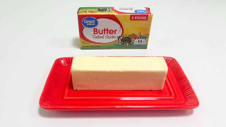 A box of Great Value Salted Butter Sticks next to a stick of butter on a red dish