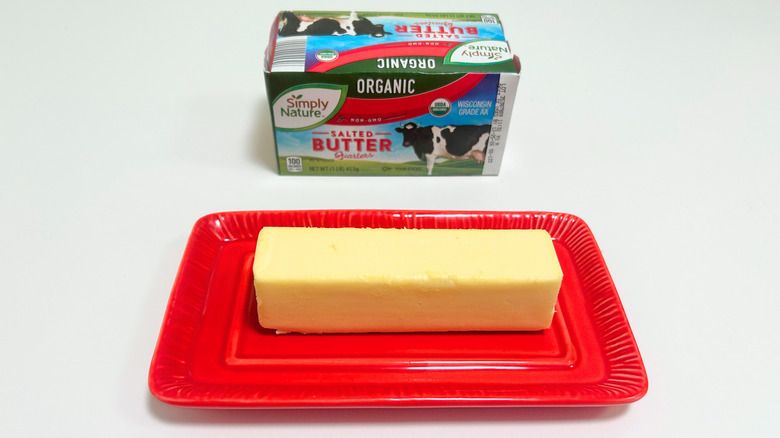 A box of Simply Nature Organic Salted Buter next to a stick of butter on a red dish