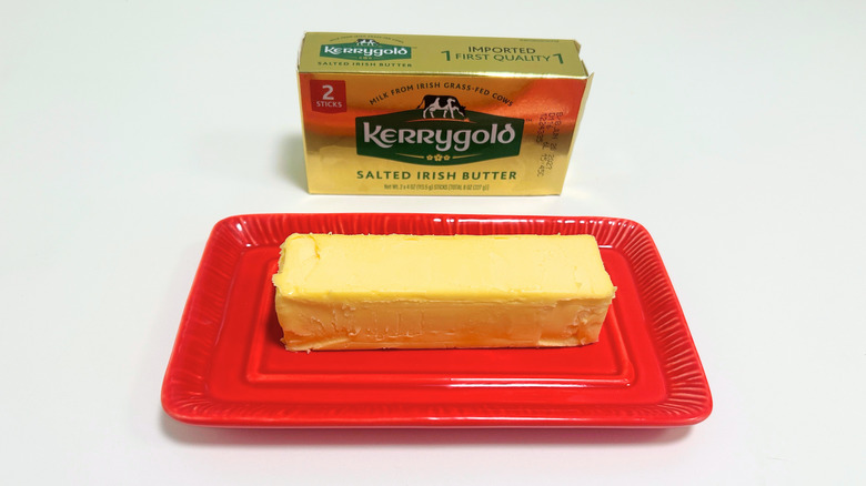 A box of Kerrygold Salted Irish Butter next to a stick of butter on a red dish