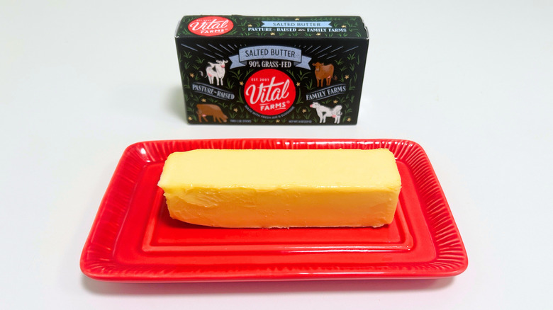 A box of Vital Farms Salted butter next to a stick of butter on a red dish