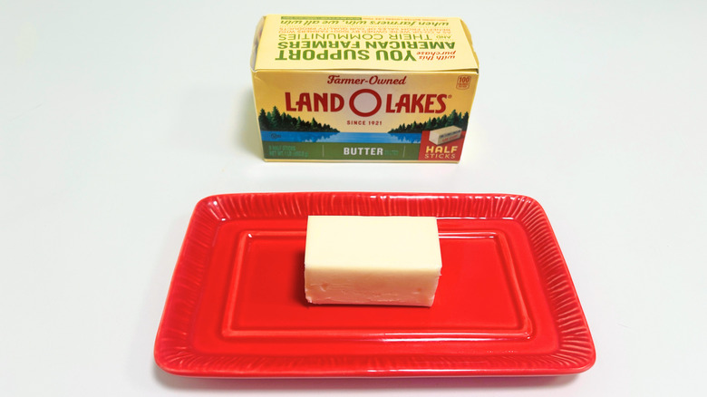 A box of Land O Lakes Butter next to a stick of butter on a red dish