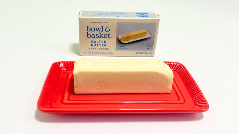 A box of Bowl and Basket Salted Butter next to a stick of butter on a red dish