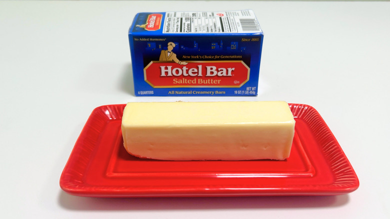 A box of Hotel Bar Salted Butter next to a stick of butter on a red dish